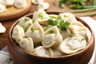 Photo of Delicious dumplings with fresh green onion and parsley on table, closeup