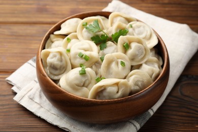 Photo of Delicious dumplings with fresh green onion and parsley on wooden table, closeup