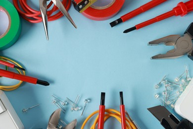 Photo of Frame of different electrical tools on light blue background, flat lay. Space for text