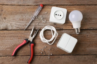 Photo of Different electrical tools on wooden table, flat lay