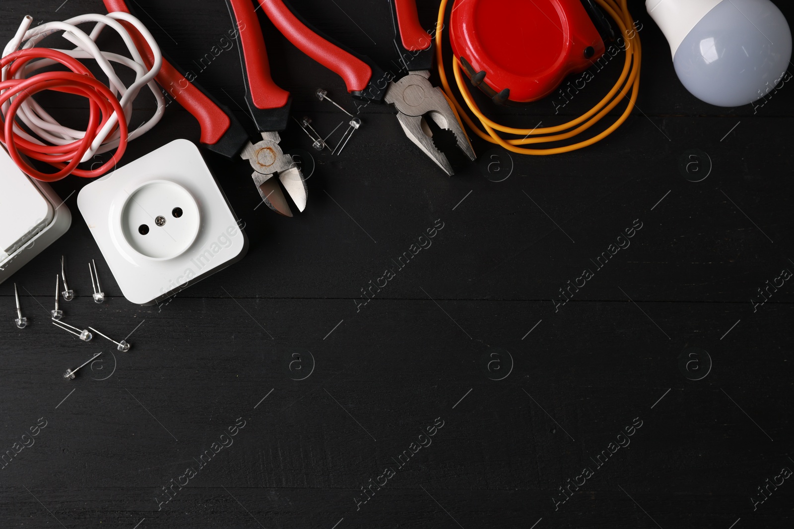 Photo of Different electrical tools on black wooden table, flat lay. Space for text