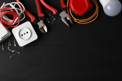 Photo of Different electrical tools on black wooden table, flat lay. Space for text