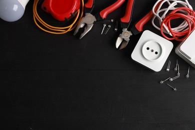 Photo of Different electrical tools on black wooden table, flat lay. Space for text