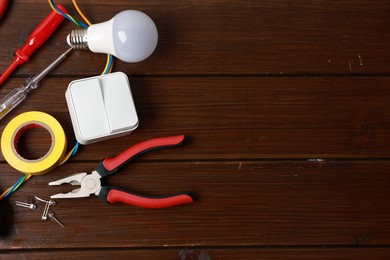 Photo of Different electrical tools on wooden table, flat lay. Space for text