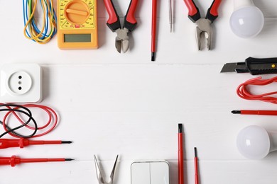 Photo of Frame of different electrical tools on white wooden table, flat lay. Space for text