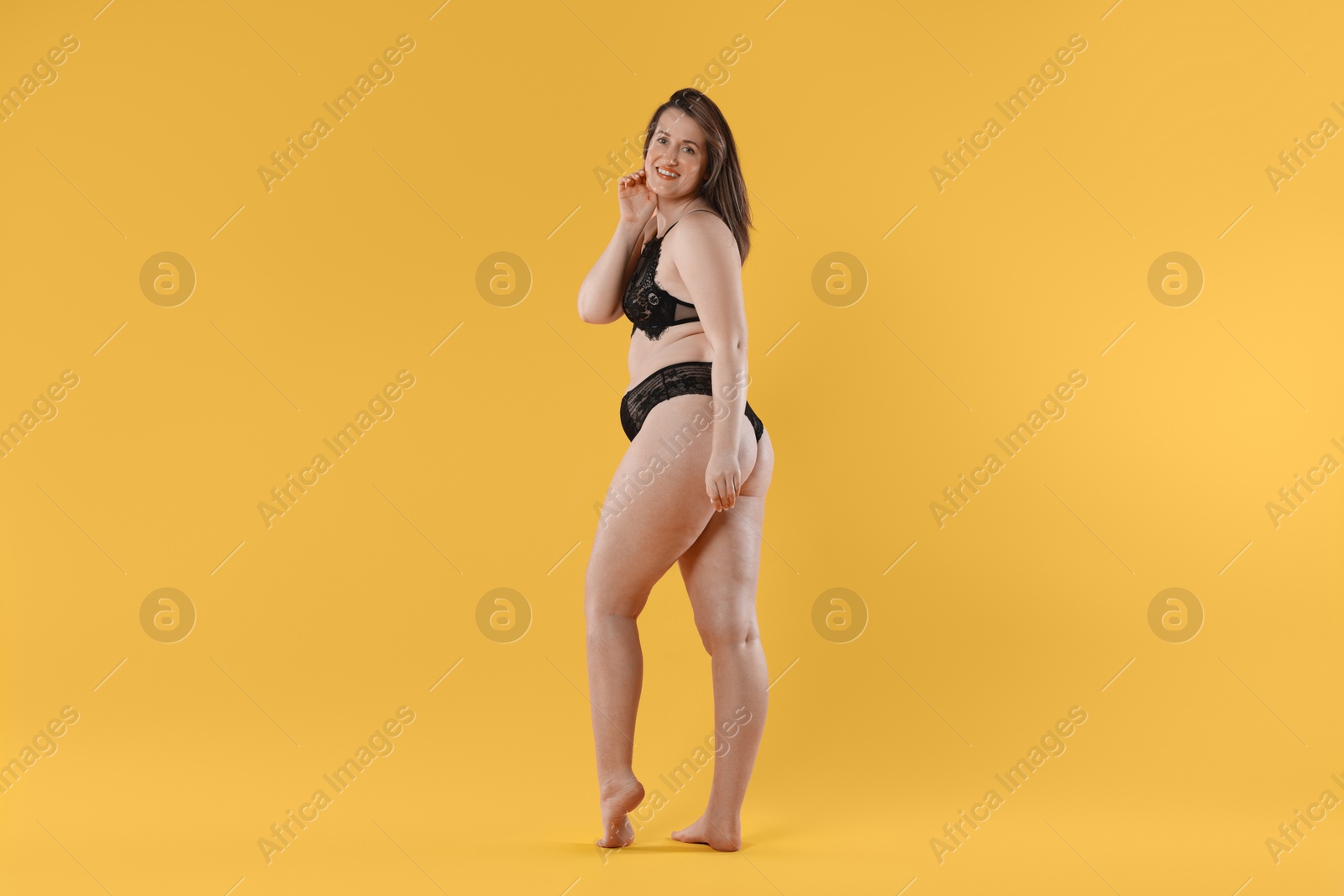 Photo of Woman in underwear on orange background. Cellulite problem