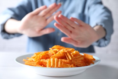 Photo of Woman refusing to eat chips at white table, selective focus. Food allergy concept