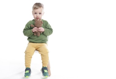 Photo of Cute little boy with toy bear on white background. Space for text