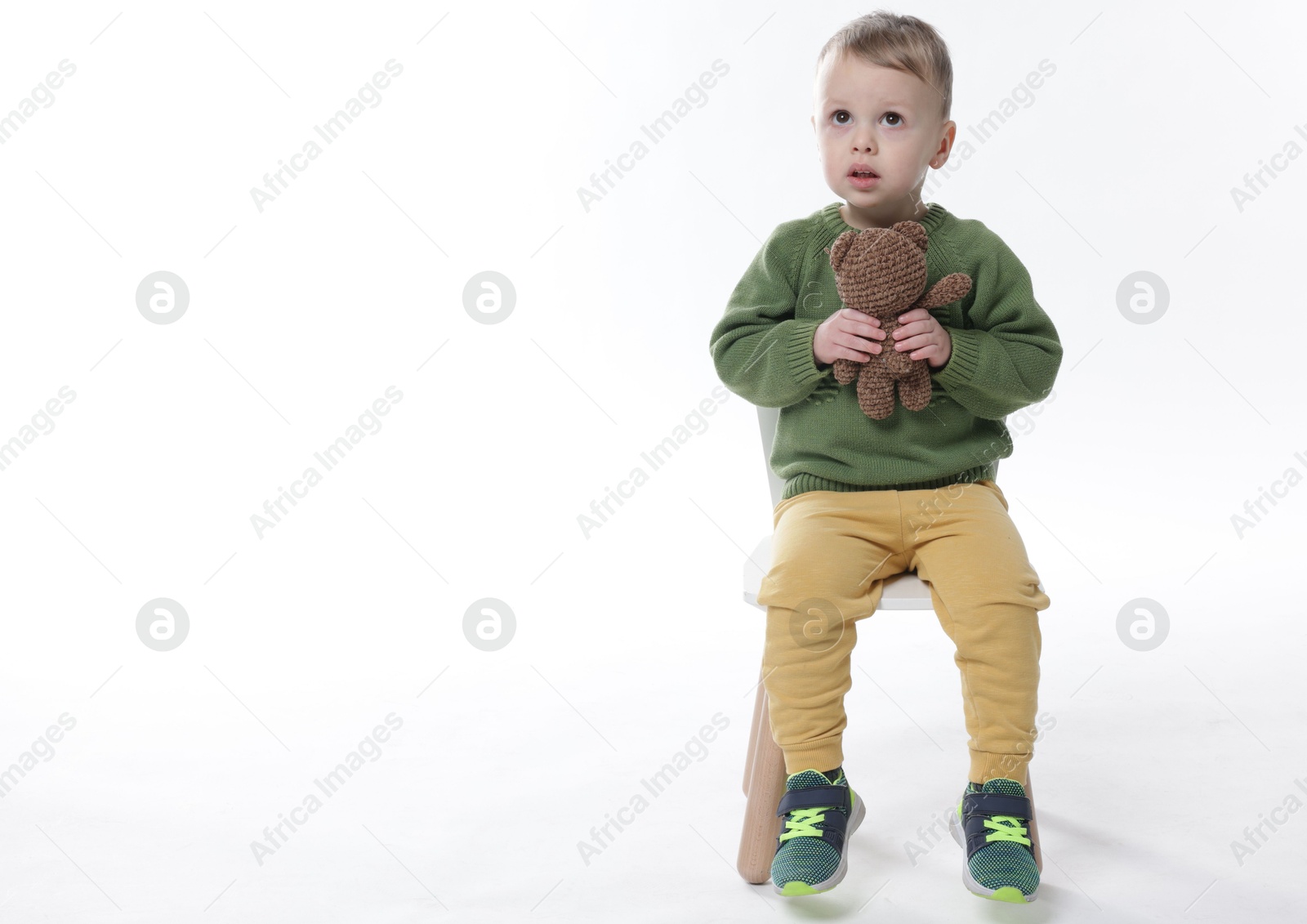 Photo of Cute little boy with toy bear on white background. Space for text