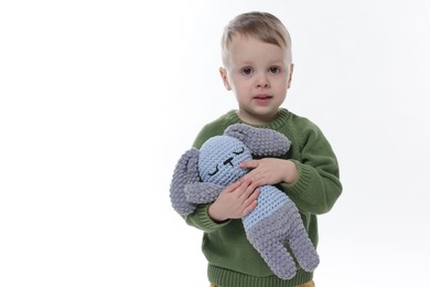 Photo of Cute little boy with toy bunny on white background. Space for text