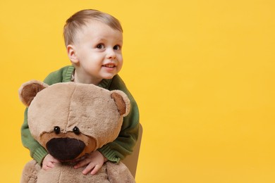 Photo of Cute little boy with toy bear on yellow background. Space for text