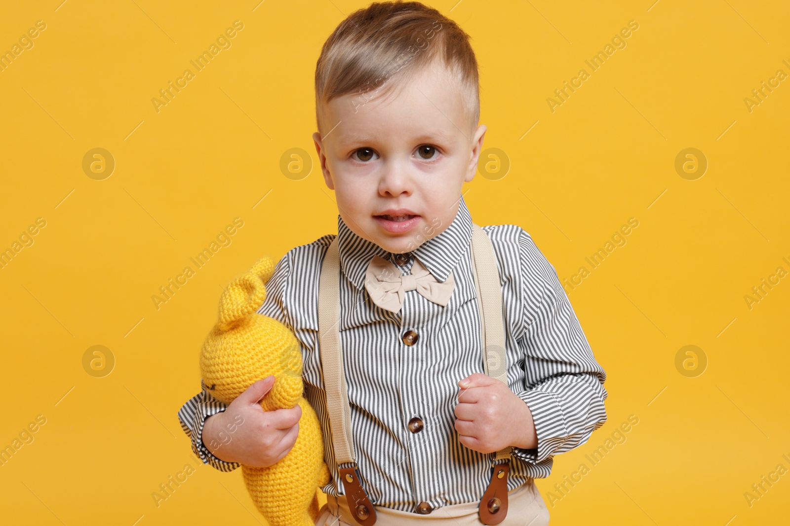 Photo of Cute little boy with toy bunny on yellow background