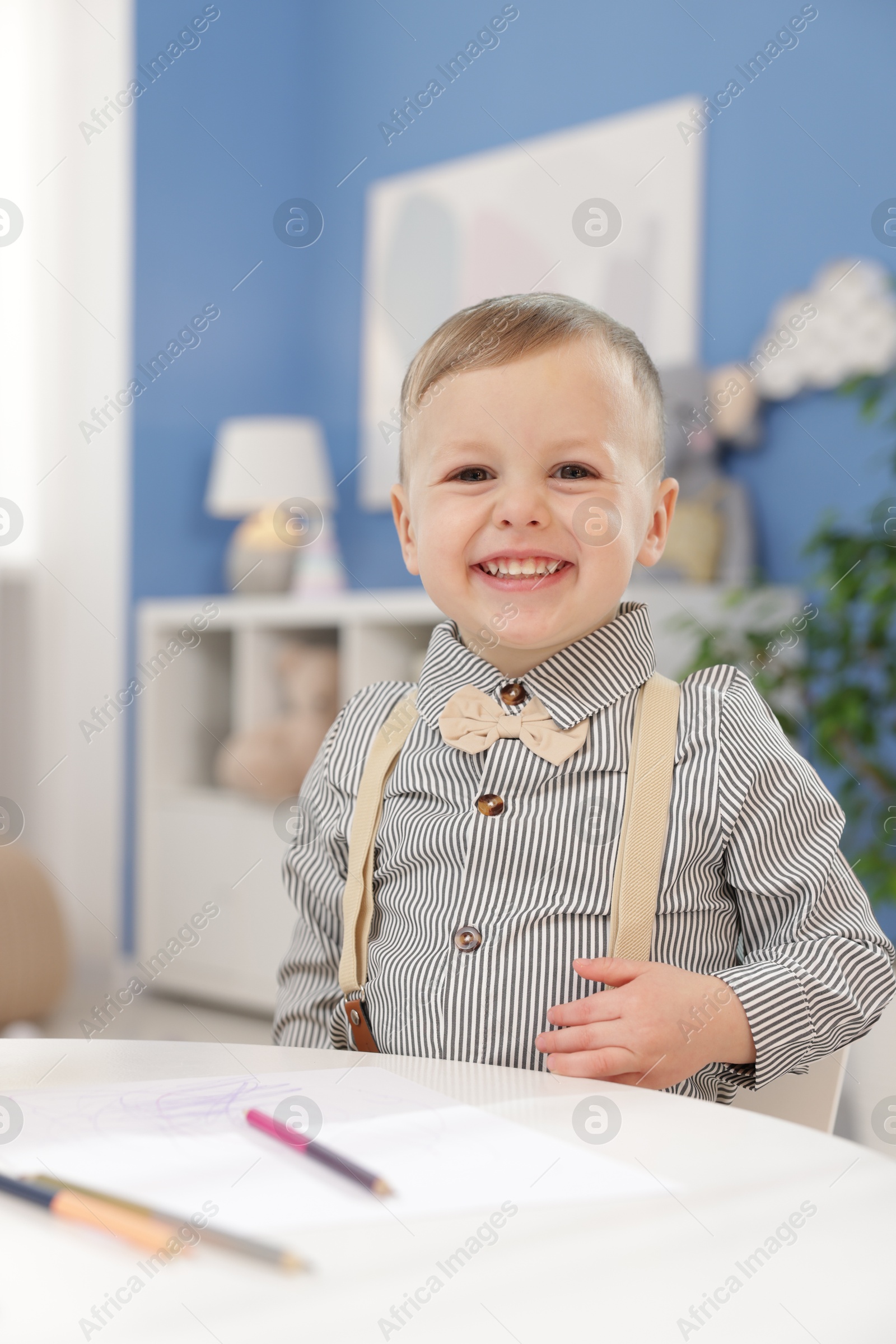 Photo of Little boy with colorful pencils at table indoors