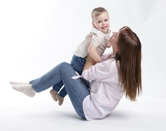 Photo of Mother and her cute son having fun on white background