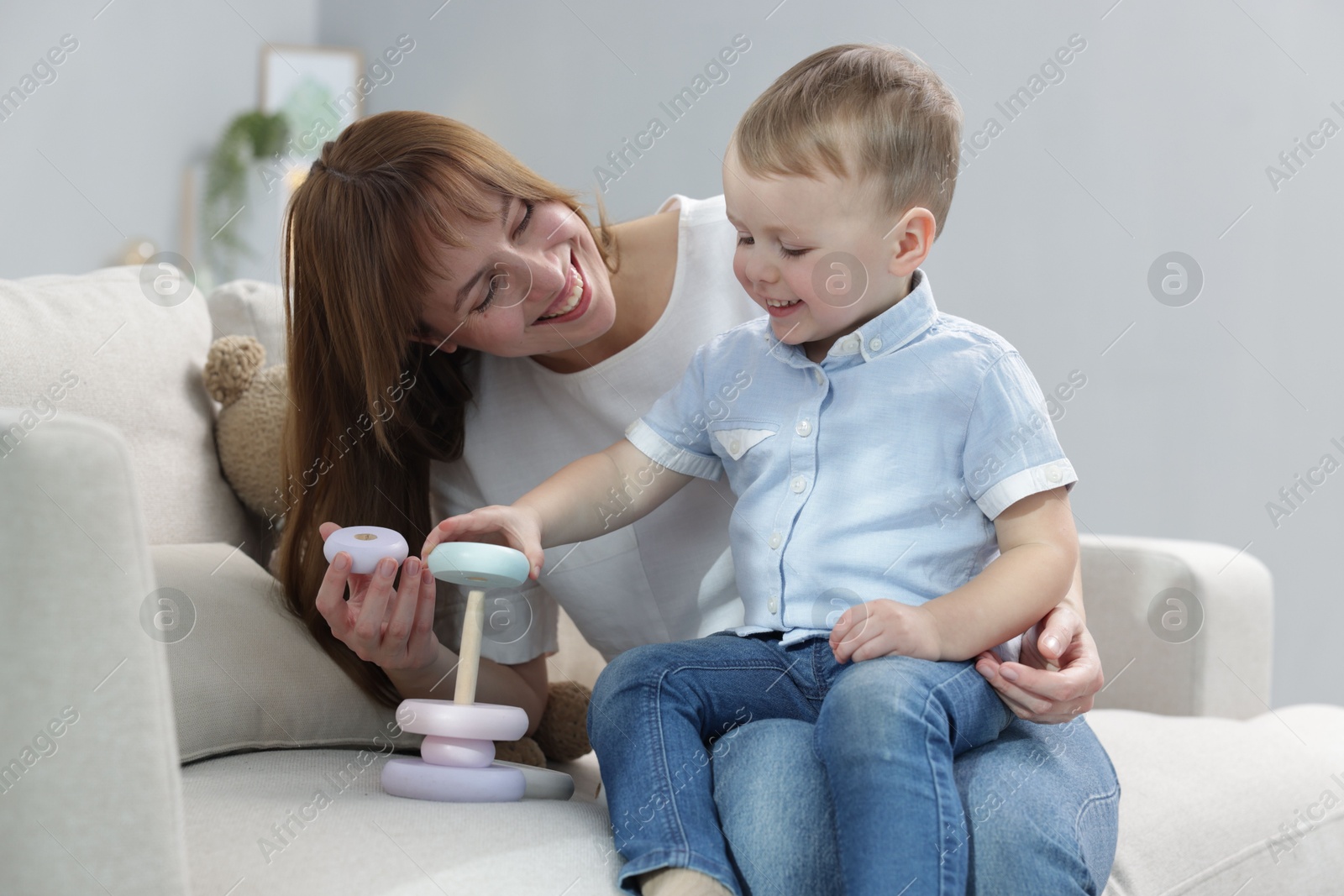 Photo of Mother and son playing with toy pyramid on sofa indoors