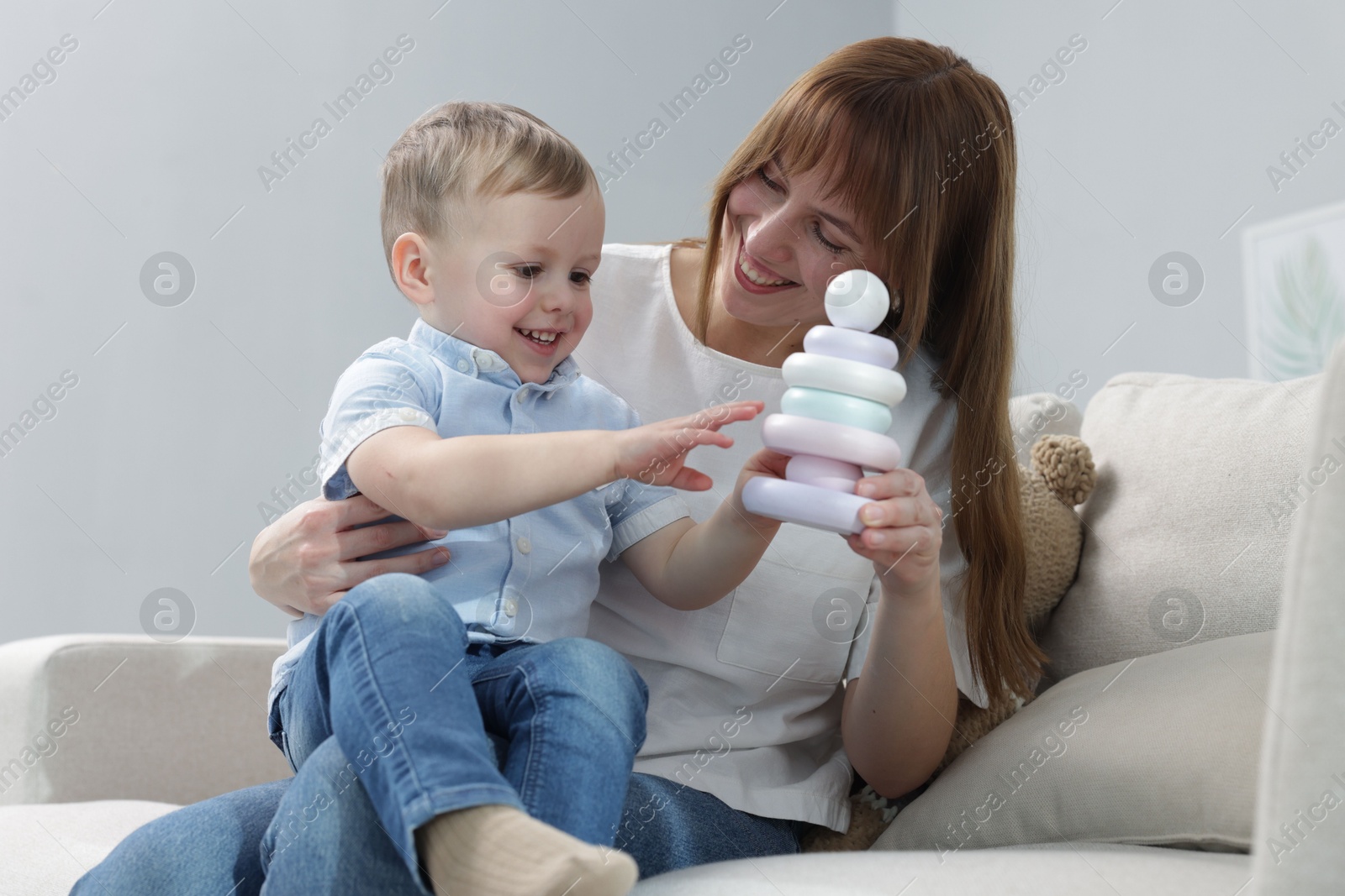 Photo of Mother and son playing with toy pyramid on sofa indoors