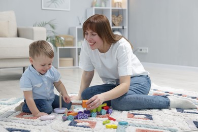 Photo of Mother and son playing with toys on floor at home