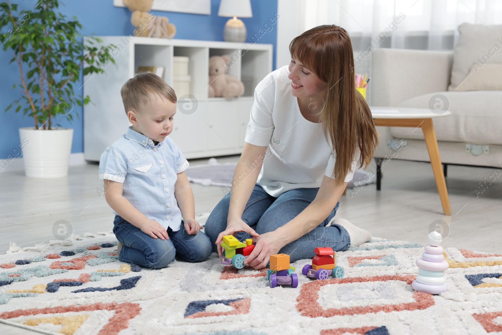 Photo of Mother and son playing with toys on floor at home