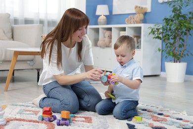 Photo of Mother and son playing with toys on floor at home