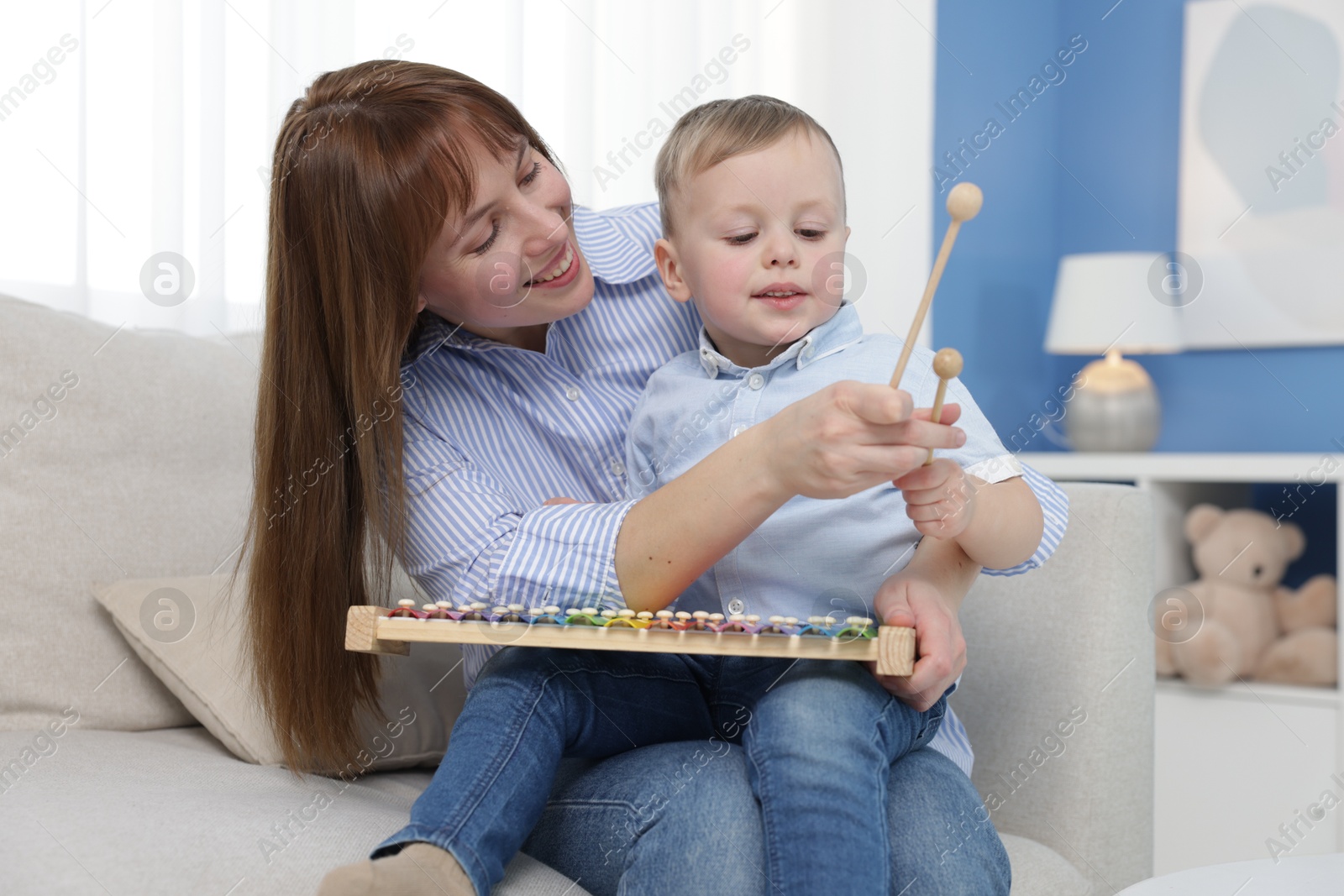 Photo of Mother and son playing with xylophone on sofa at home