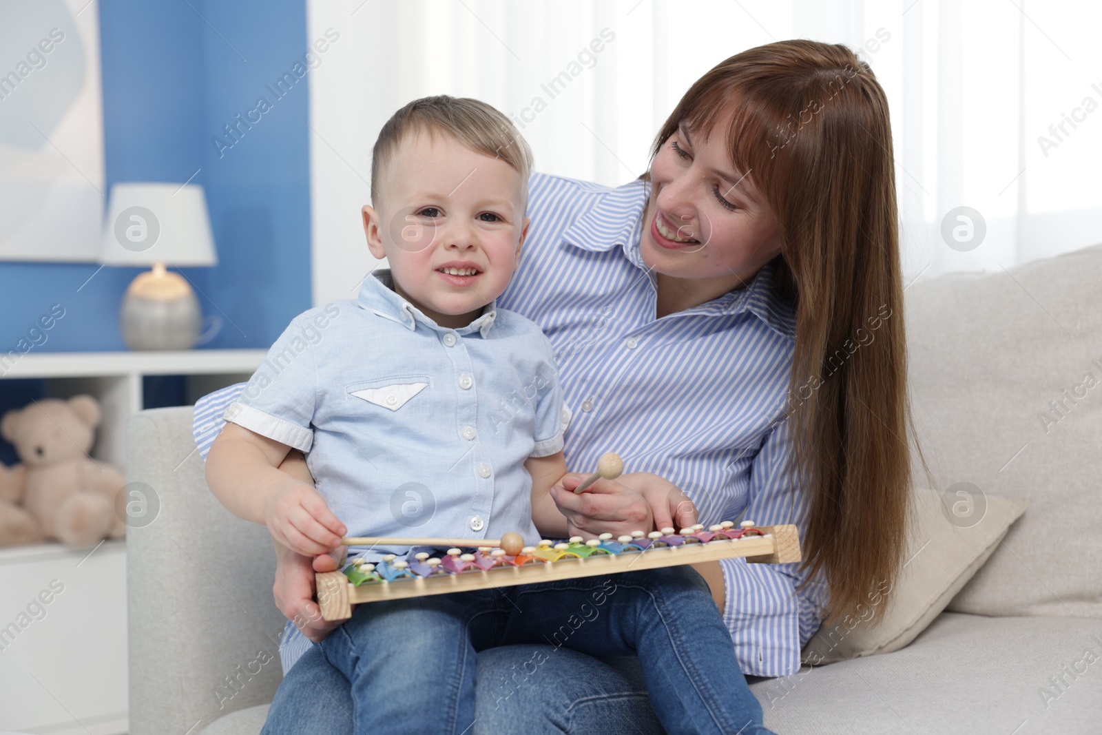 Photo of Mother and son playing with xylophone on sofa at home