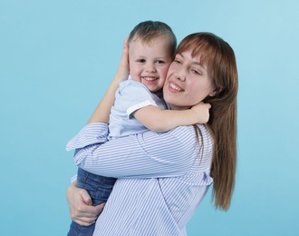 Photo of Mother and her cute son on light blue background