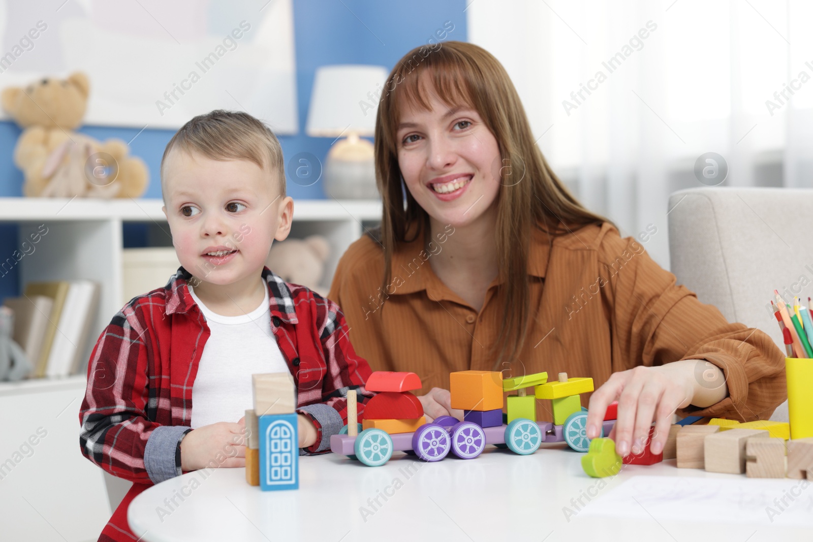 Photo of Mother and son playing with toys at table indoors