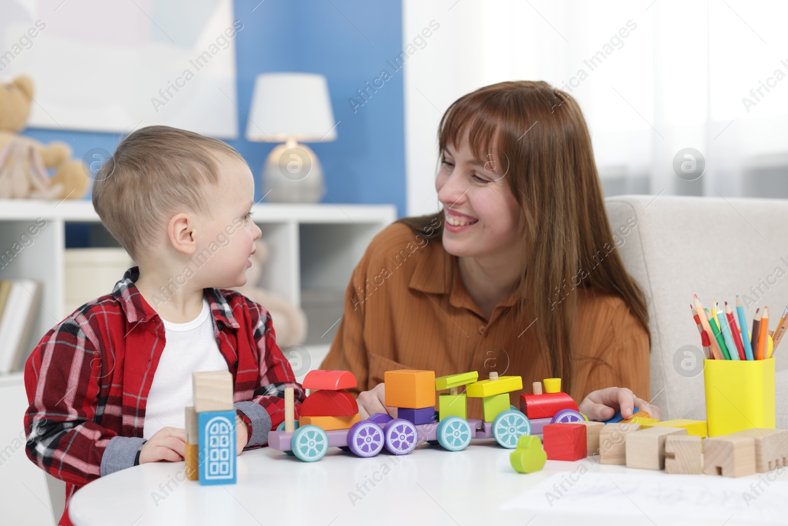 Photo of Mother and son playing with toys at table indoors