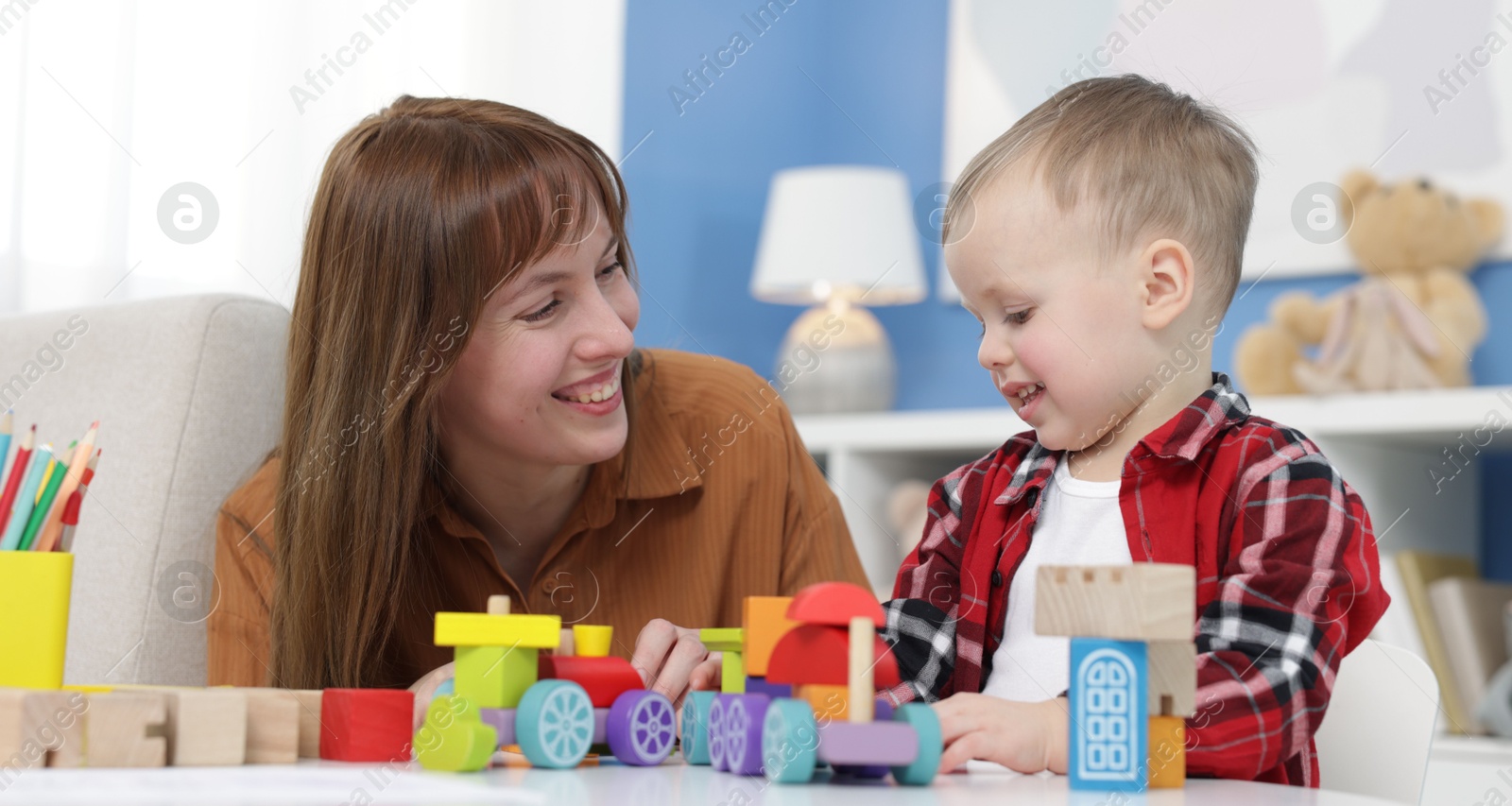 Photo of Mother and son playing with toys at table indoors