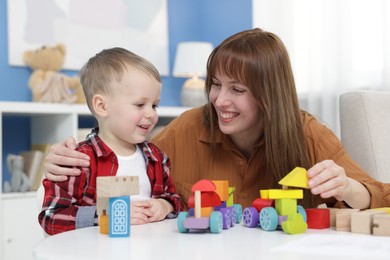 Photo of Mother and son playing with toys at table indoors