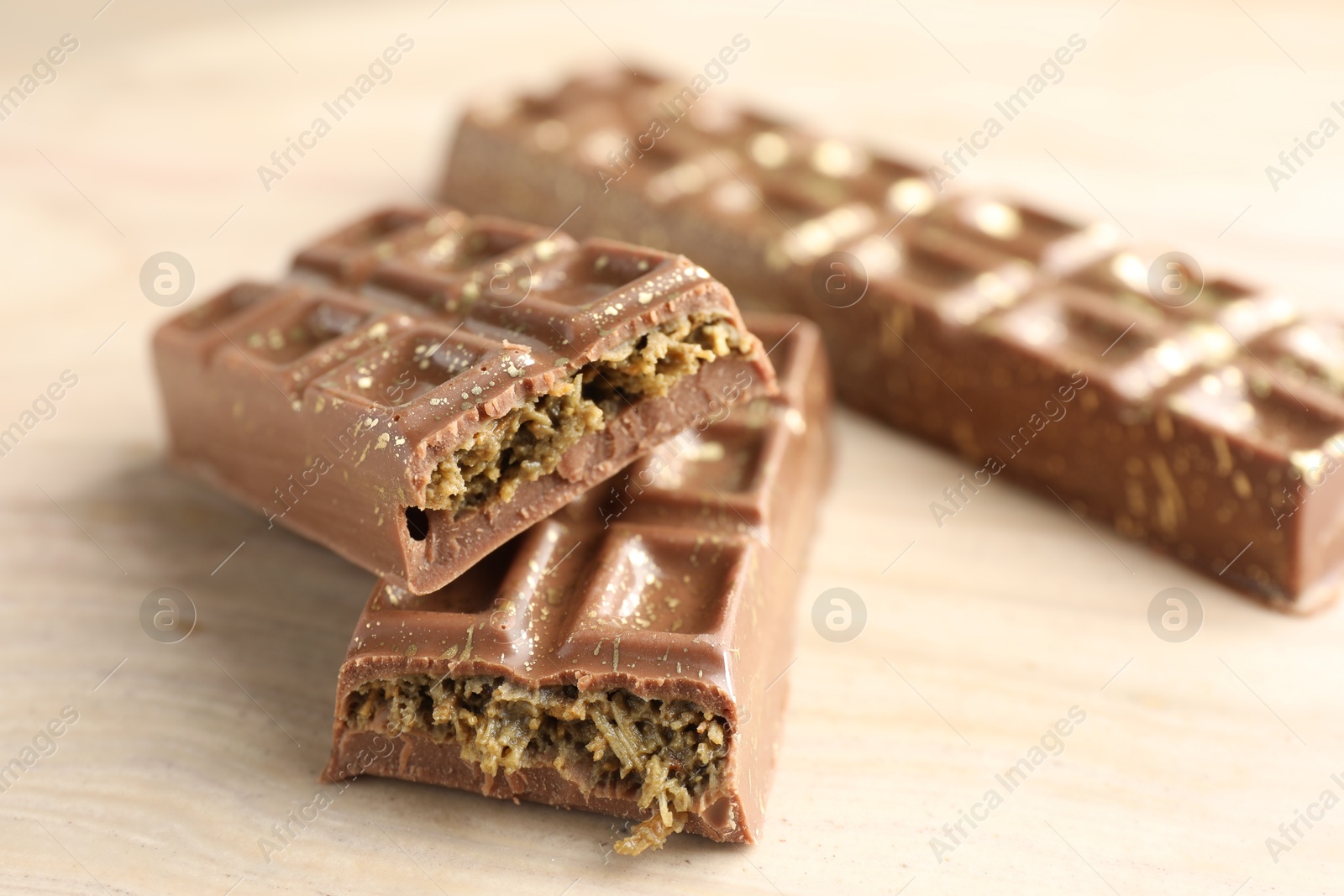 Photo of Delicious Dubai chocolate bars on wooden table, closeup