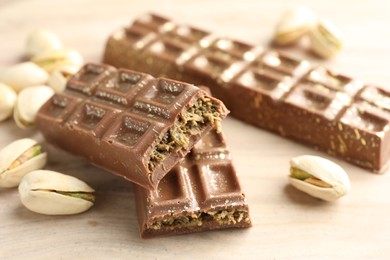 Photo of Delicious Dubai chocolate bars and pistachios on wooden table, closeup