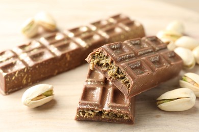 Photo of Delicious Dubai chocolate bars and pistachios on wooden table, closeup