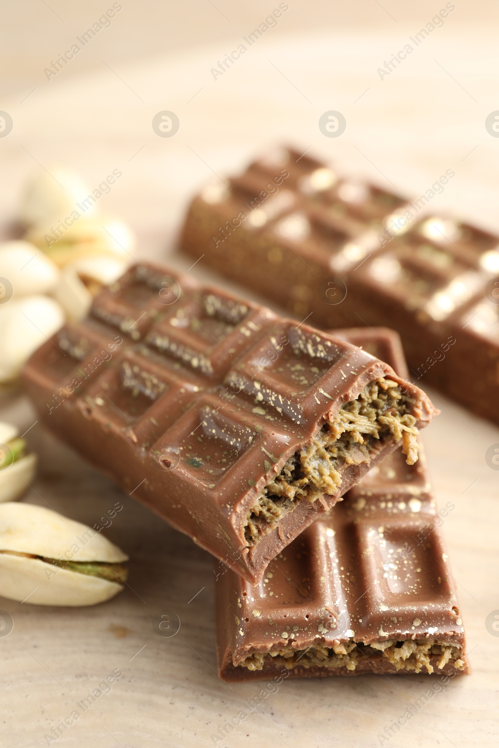 Photo of Delicious Dubai chocolate bars and pistachios on wooden table, closeup