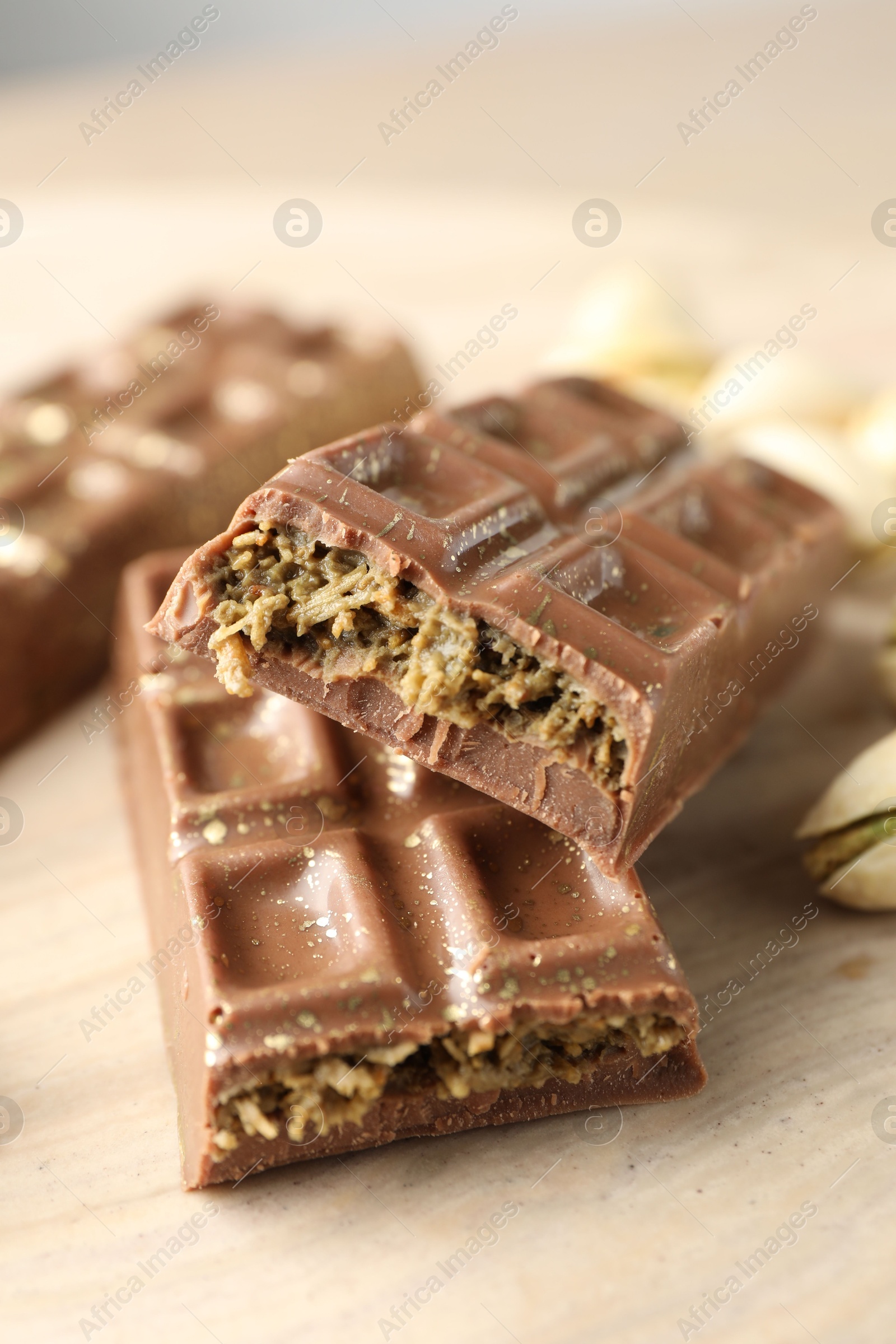 Photo of Delicious Dubai chocolate bars and pistachios on wooden table, closeup