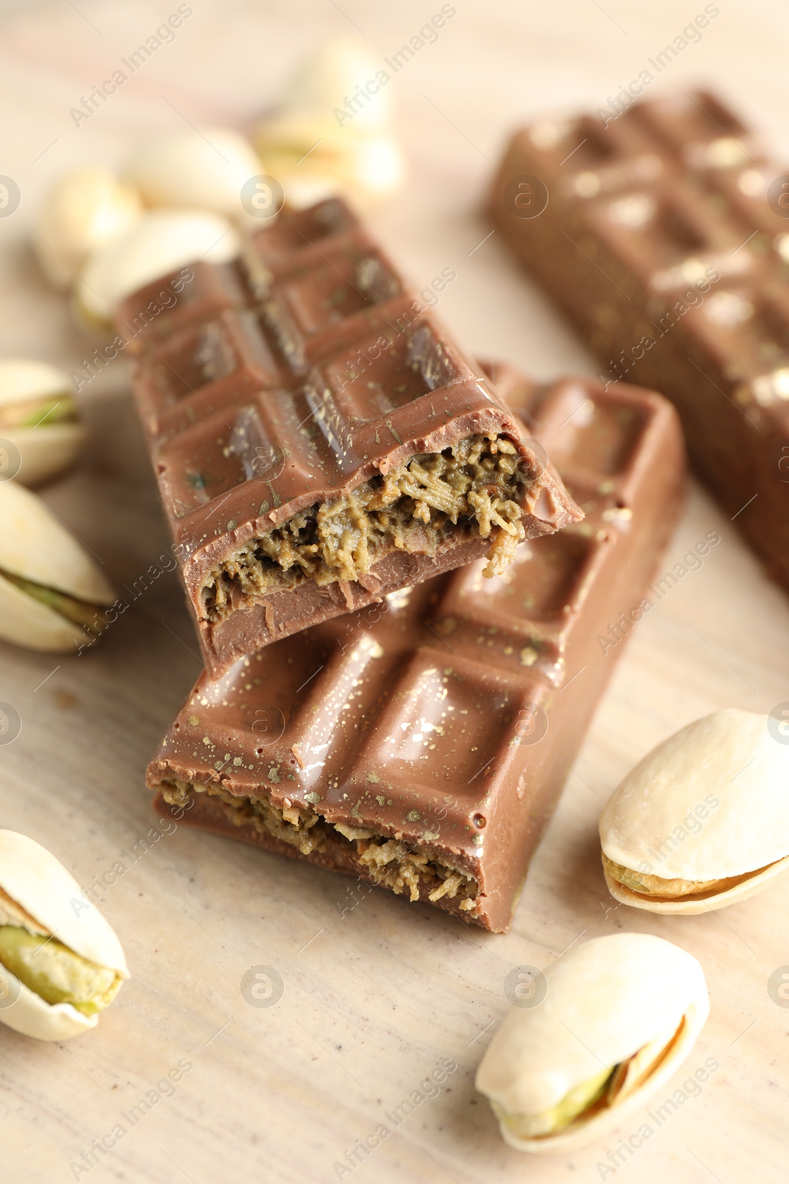 Photo of Delicious Dubai chocolate bars and pistachios on wooden table, closeup