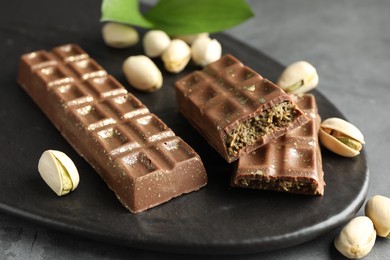 Photo of Delicious Dubai chocolate bars and pistachios on grey table, closeup