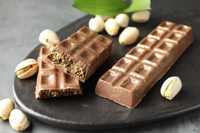 Photo of Delicious Dubai chocolate bars and pistachios on grey table, closeup