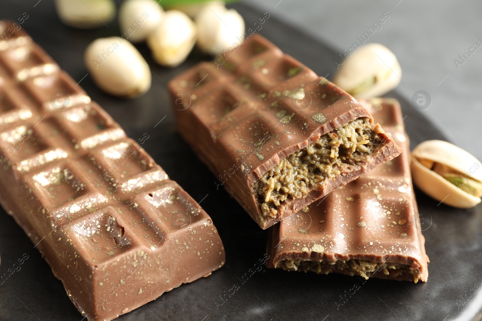 Photo of Delicious Dubai chocolate bars and pistachios on table, closeup