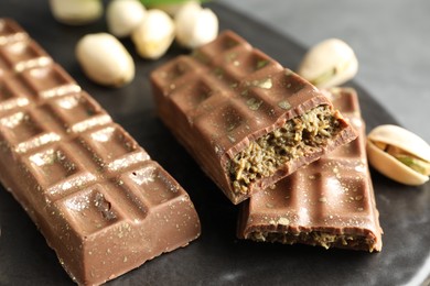 Photo of Delicious Dubai chocolate bars and pistachios on table, closeup