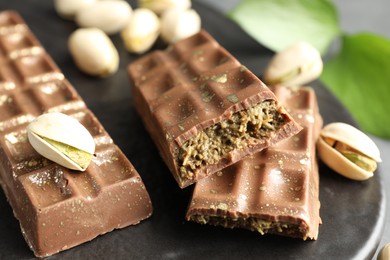 Photo of Delicious Dubai chocolate bars and pistachios on table, closeup