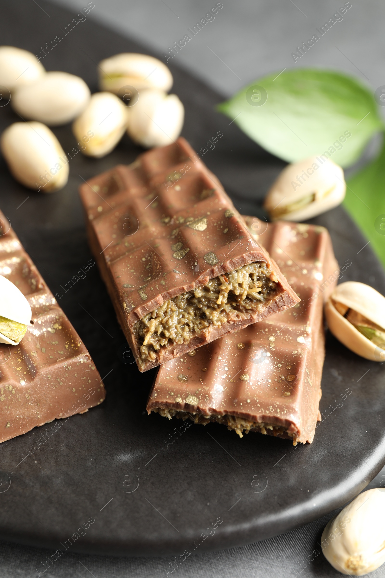 Photo of Delicious Dubai chocolate bars and pistachios on table, closeup