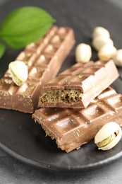 Photo of Delicious Dubai chocolate bars and pistachios on table, closeup