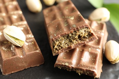 Photo of Delicious Dubai chocolate bars and pistachios on table, closeup