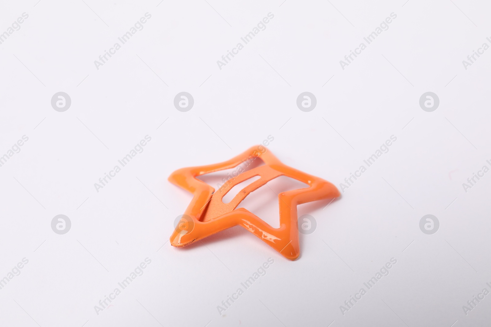 Photo of One orange star shaped hair clip on white background