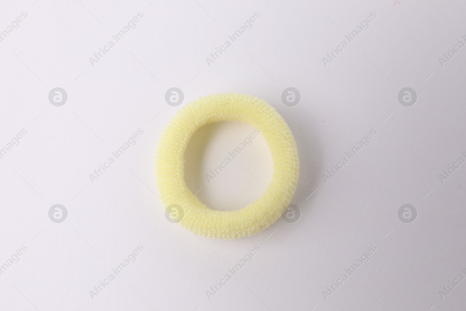 Photo of One yellow hair tie on white background, top view