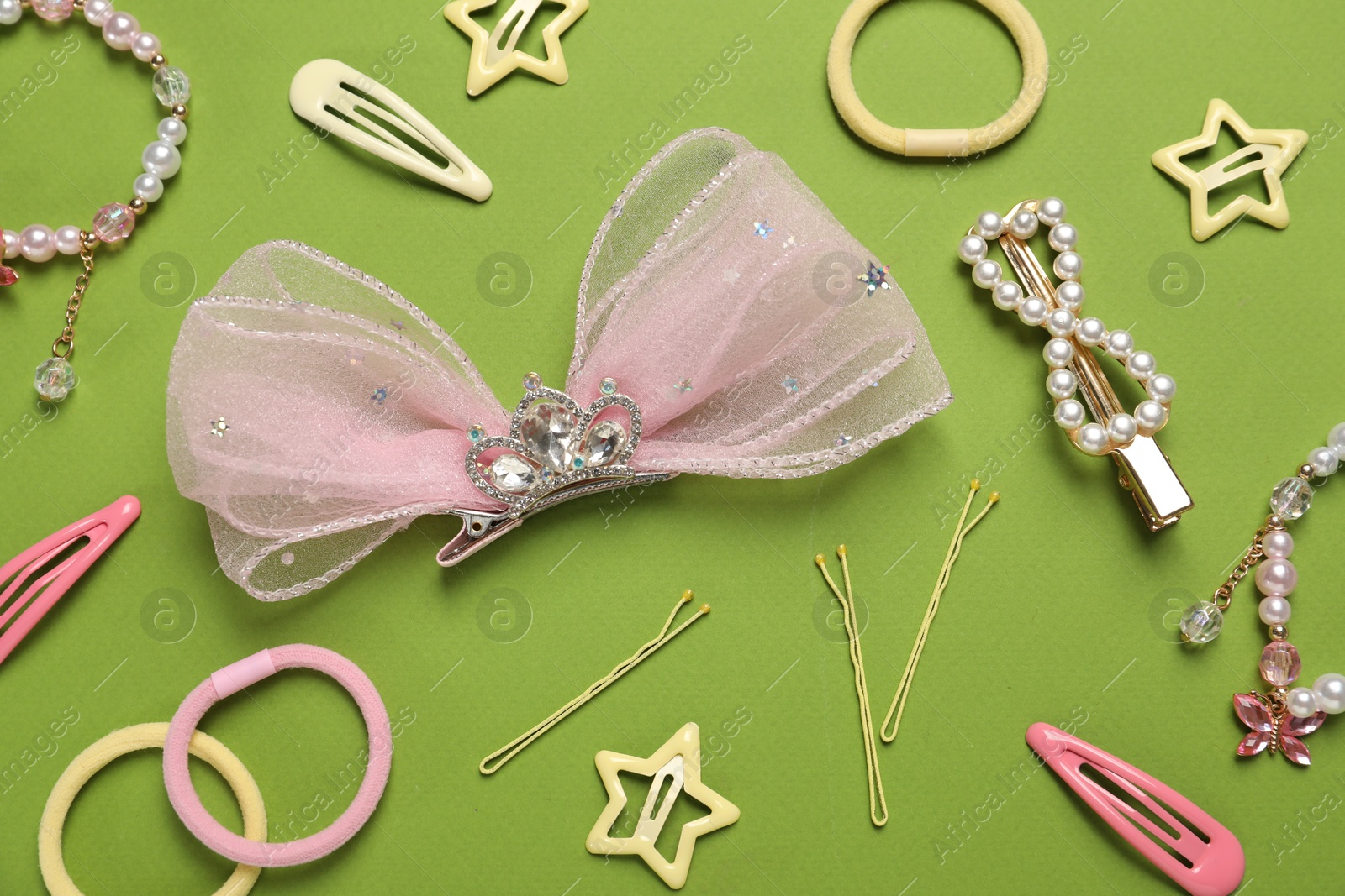 Photo of Cute hair accessories on green background, flat lay