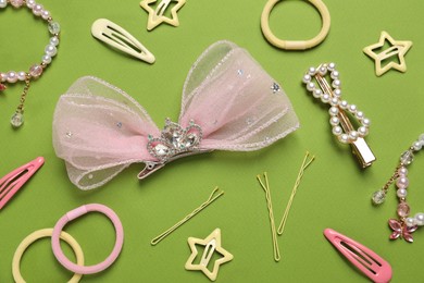 Photo of Cute hair accessories on green background, flat lay