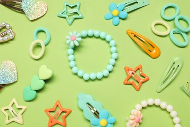 Photo of Cute hair accessories on green background, flat lay