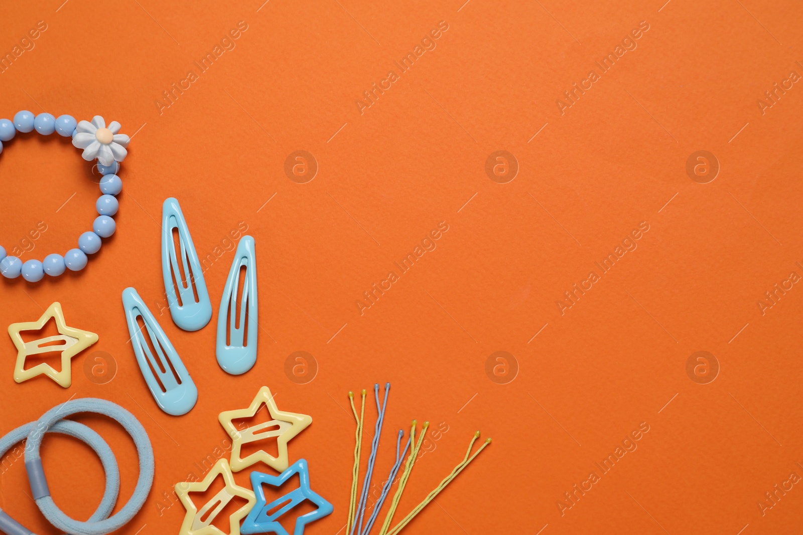 Photo of Cute hair accessories on orange background, flat lay. Space for text